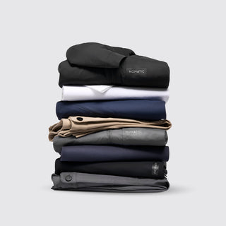 NOMATIC Apparel Bundle Builder collection banner, stack of folded NOMATIC apparel in black, white, navy, and tan
