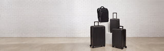 NOMATIC Bundles collection banner, a matching set of black hardside luggage and a backpack displayed on white pedestals