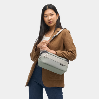 NOMATIC Luma Camera Sling 9L in sage, worn cross-body by model, front view