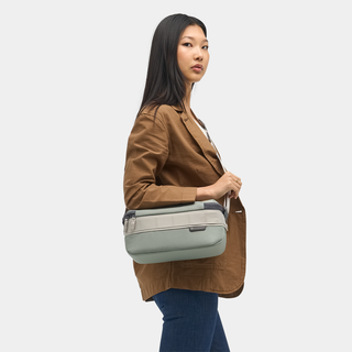 NOMATIC Luma Camera Sling 9L in sage, worn cross-body by model, side view