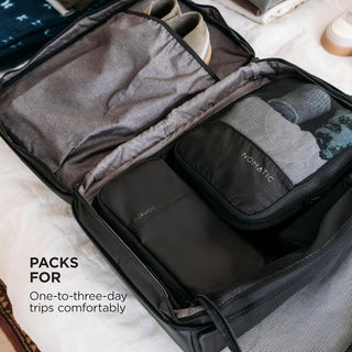 Open suitcase with travel packing cubes labeled 'NOMATIC' on a marble surface.