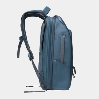 A slate blue backpack shown from a side profile view against a light gray background.